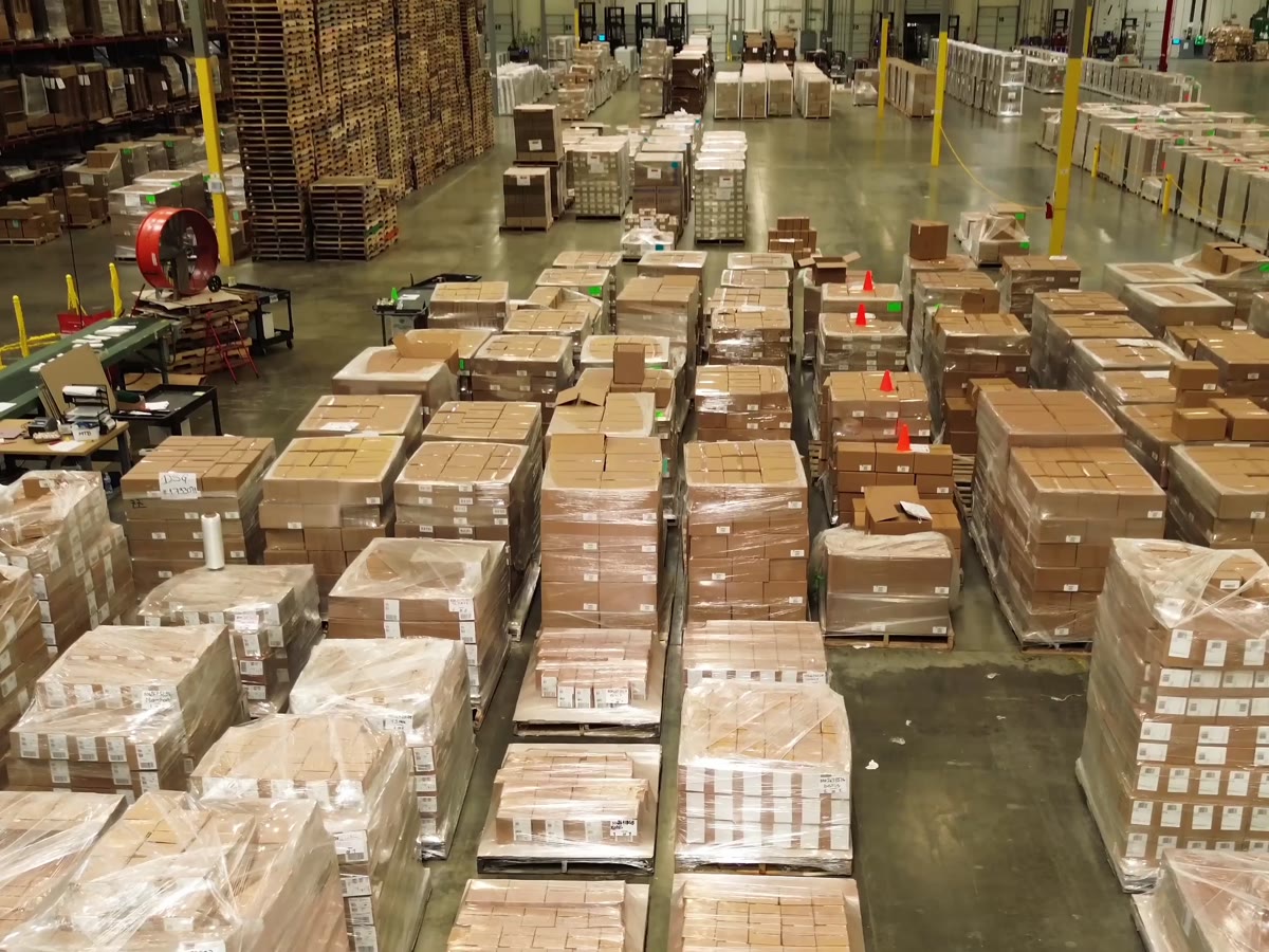 Rows of shrink-wrapped, labeled case-pack pallets staged for retail and club shipment on a Productiv warehouse floor